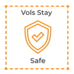 An orange shield with a checkmark inside with the words, "Vols Stay Safe."